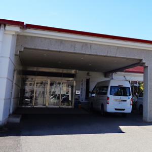 白い車寄せ付きの玄関・エントランス。ガラス戸と駐車スペースが見える